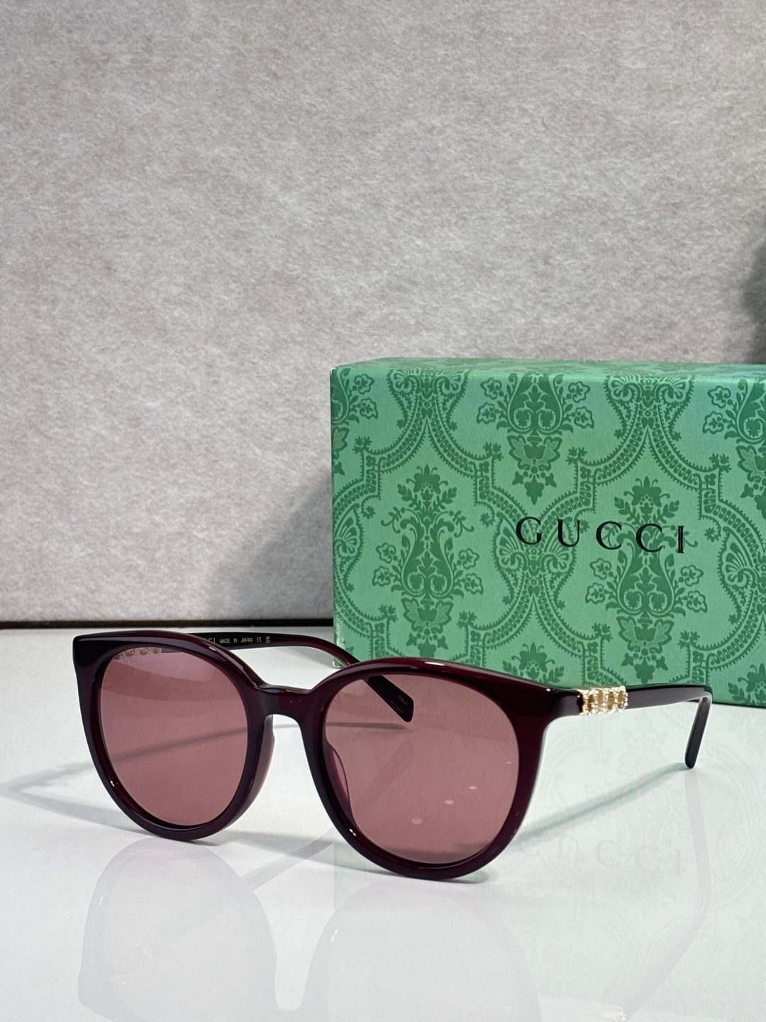 Gucci sunglasses with maroon frames and rose lenses, gold temple detailing