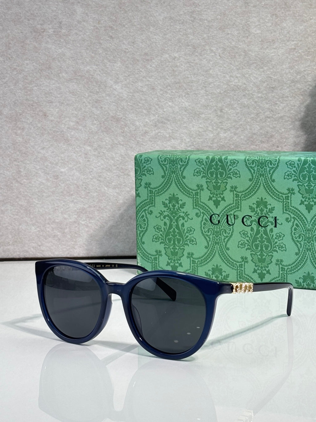 Gucci sunglasses with dark blue frames and dark lenses, gold temple accents