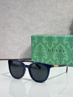Gucci sunglasses with dark blue frames and dark lenses, gold temple accents