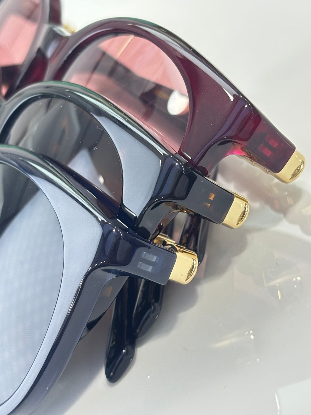 Gucci sunglasses side view with maroon lens rim, dark frame, gold logo accents