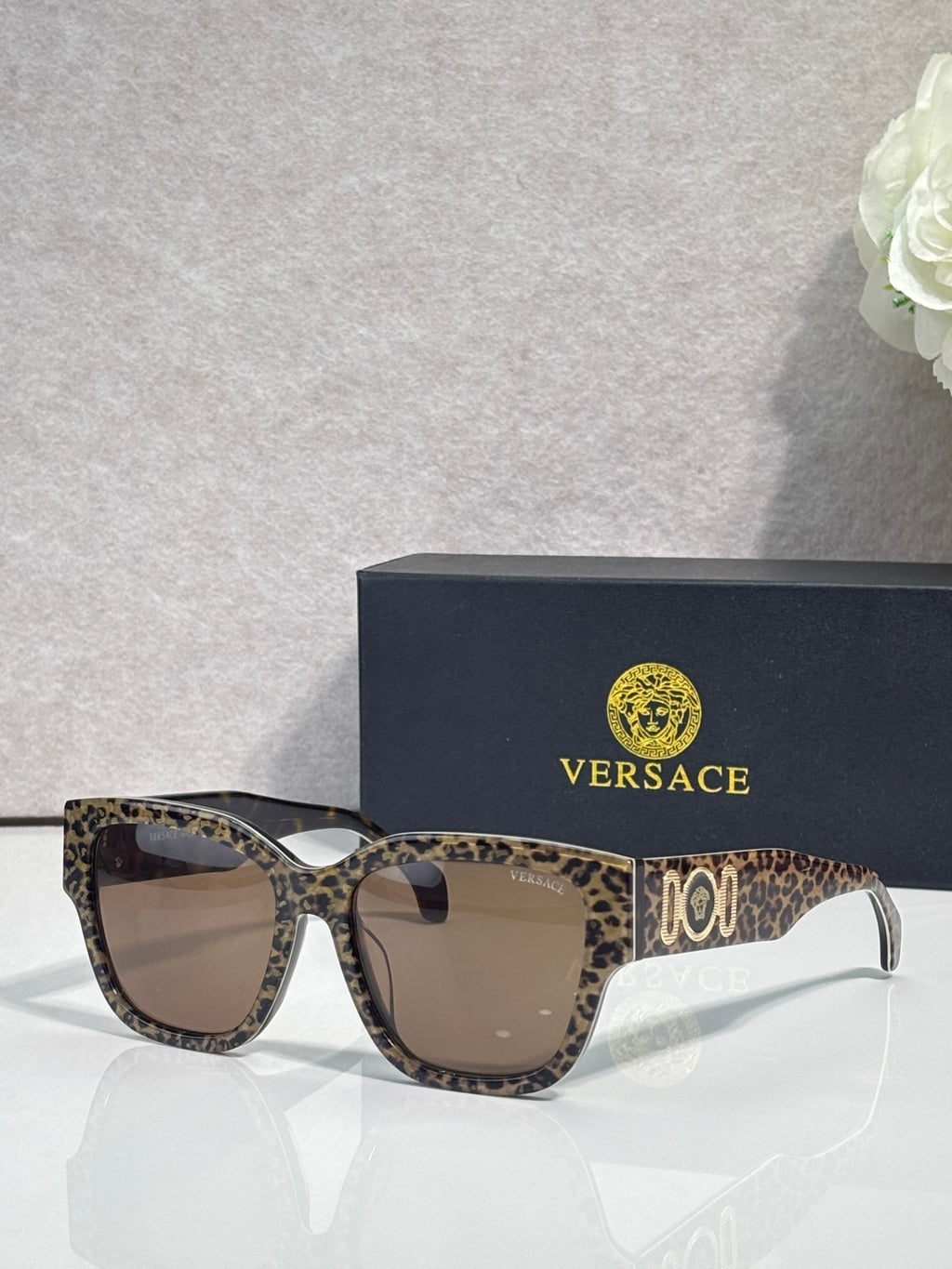 Versace sunglasses with leopard-print frame and brown-tinted lenses, gold “101” logo.