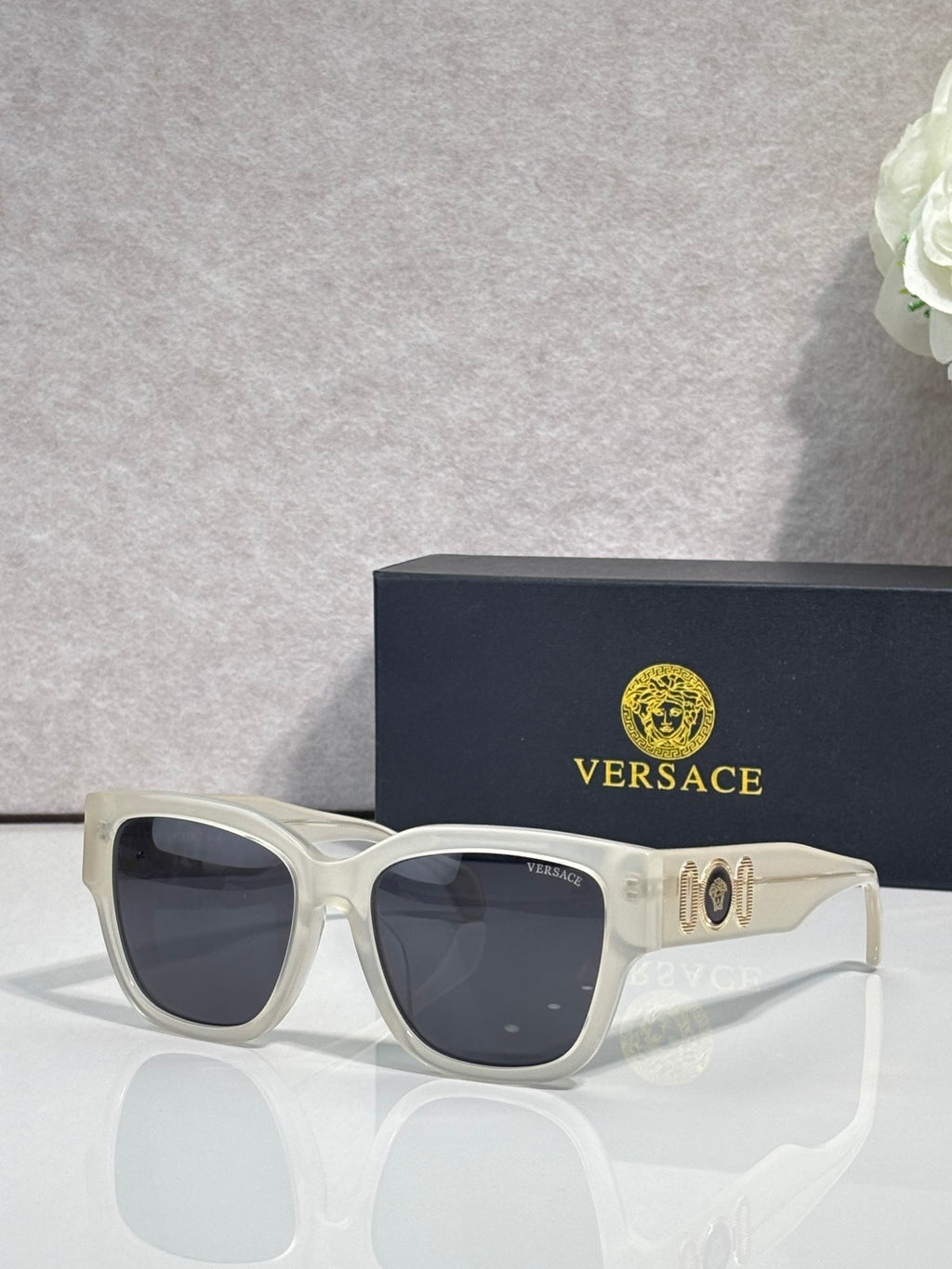 Versace sunglasses with white frame and dark lenses, gold “101” logo on temple.