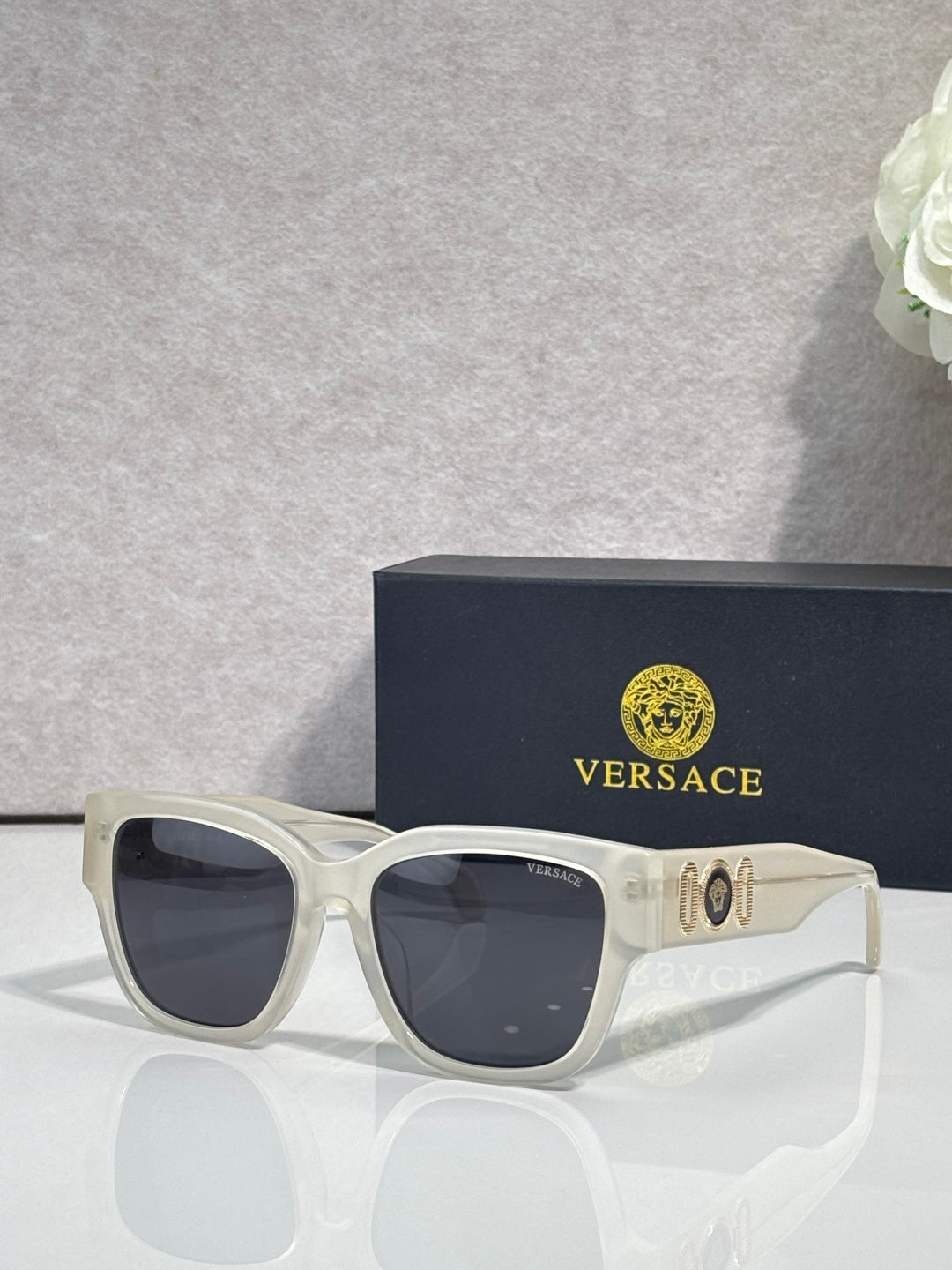 Versace sunglasses with white frame and dark lenses, gold “101” logo on temple.