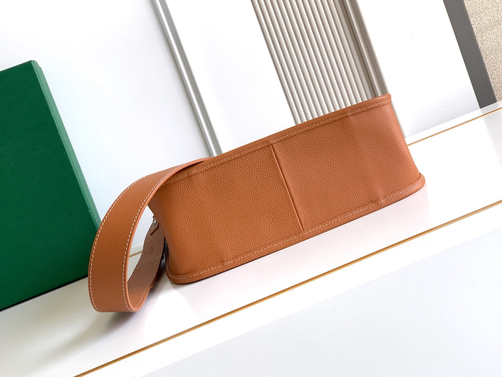 Tan leather clutch-style bag with long strap and top panel