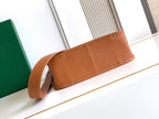 Tan leather clutch-style bag with long strap and top panel