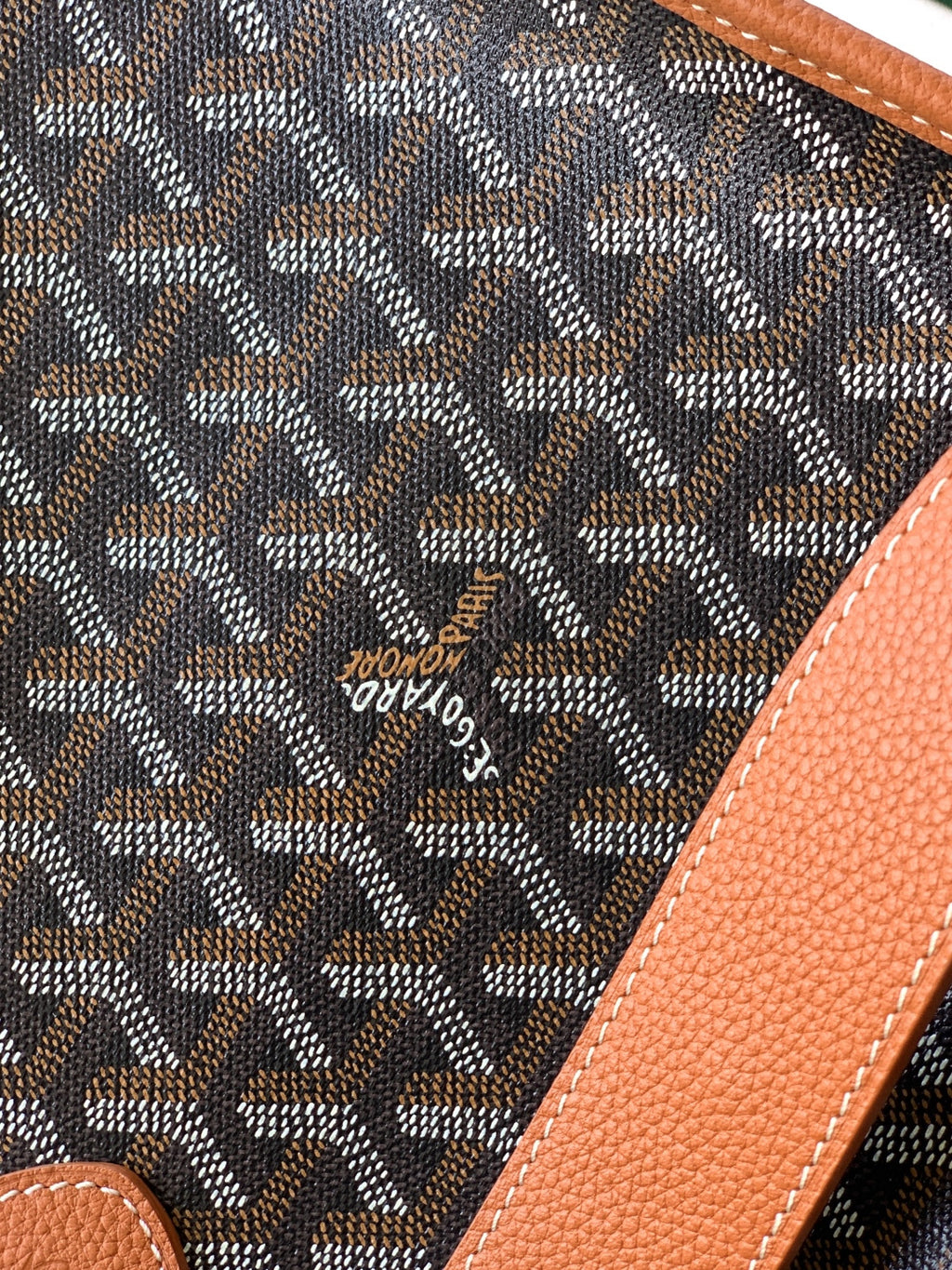 Monogram fabric panel with tan leather trim and small embossed emblem, close-up