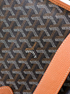 Monogram fabric panel with tan leather trim and small embossed emblem, close-up