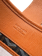 Tan leather side panel with embossed logo and stitched seam, close-up