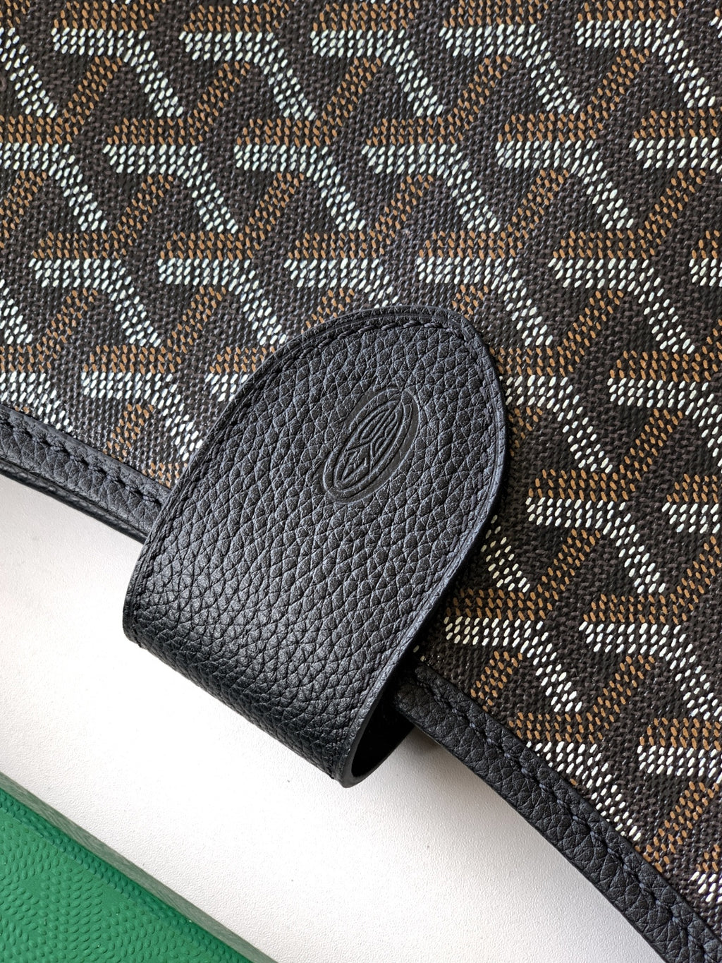 Black leather clasp detail on patterned shoulder bag with textured trim