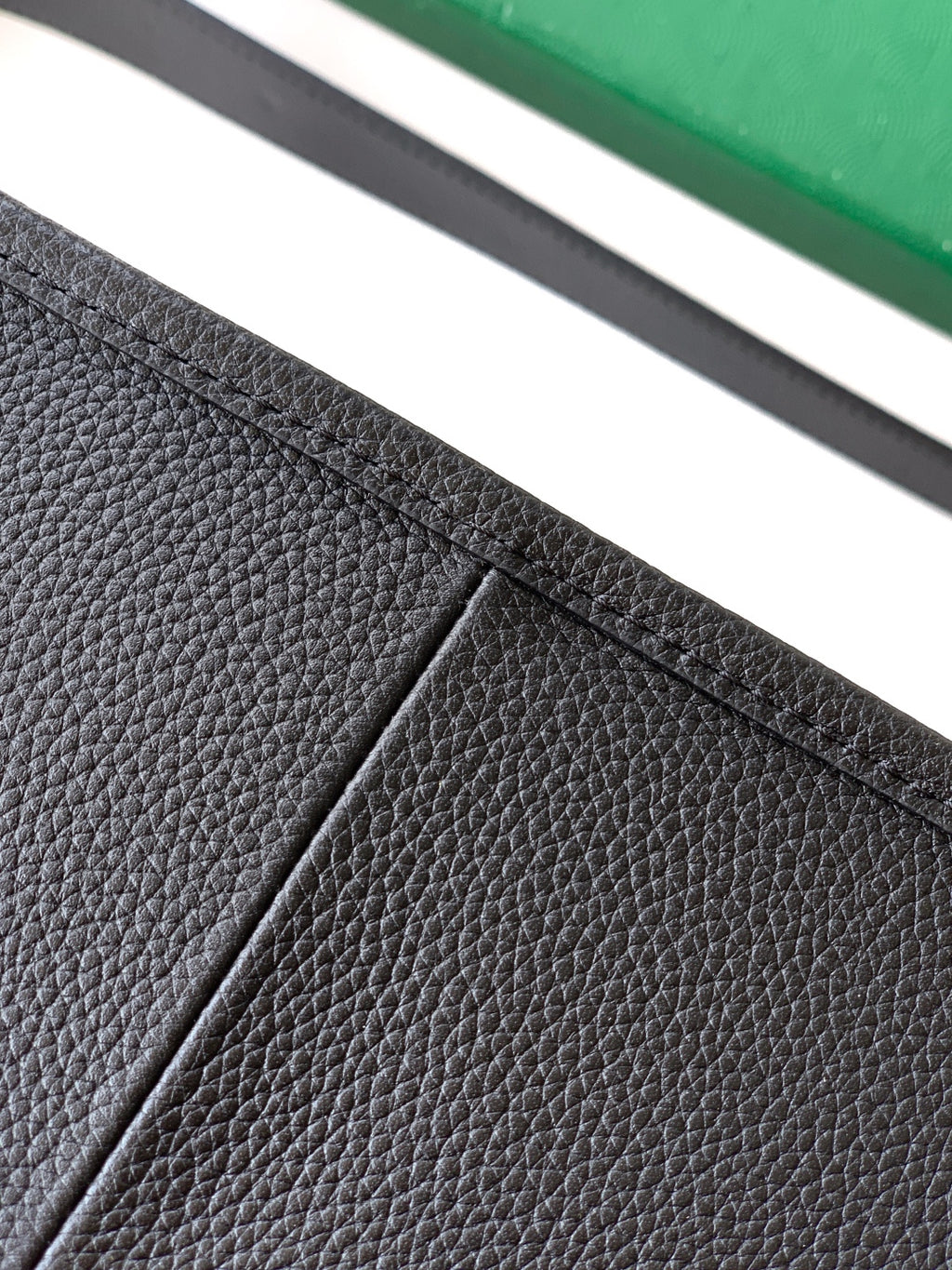 Black leather bag panel with visible seam and textured grain detail
