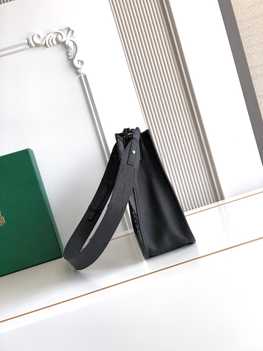 Black leather tote-style bag with long shoulder strap and top opening