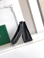 Black leather tote-style bag with long shoulder strap and top opening