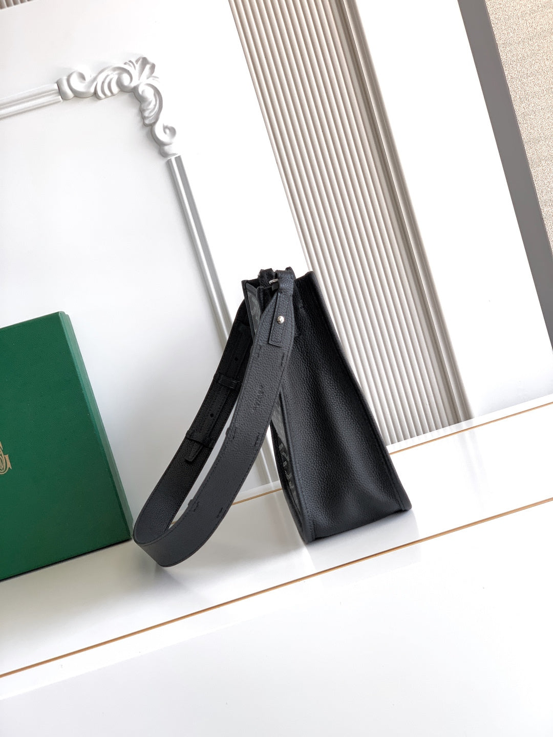 Black leather tote-style bag with long shoulder strap and top opening