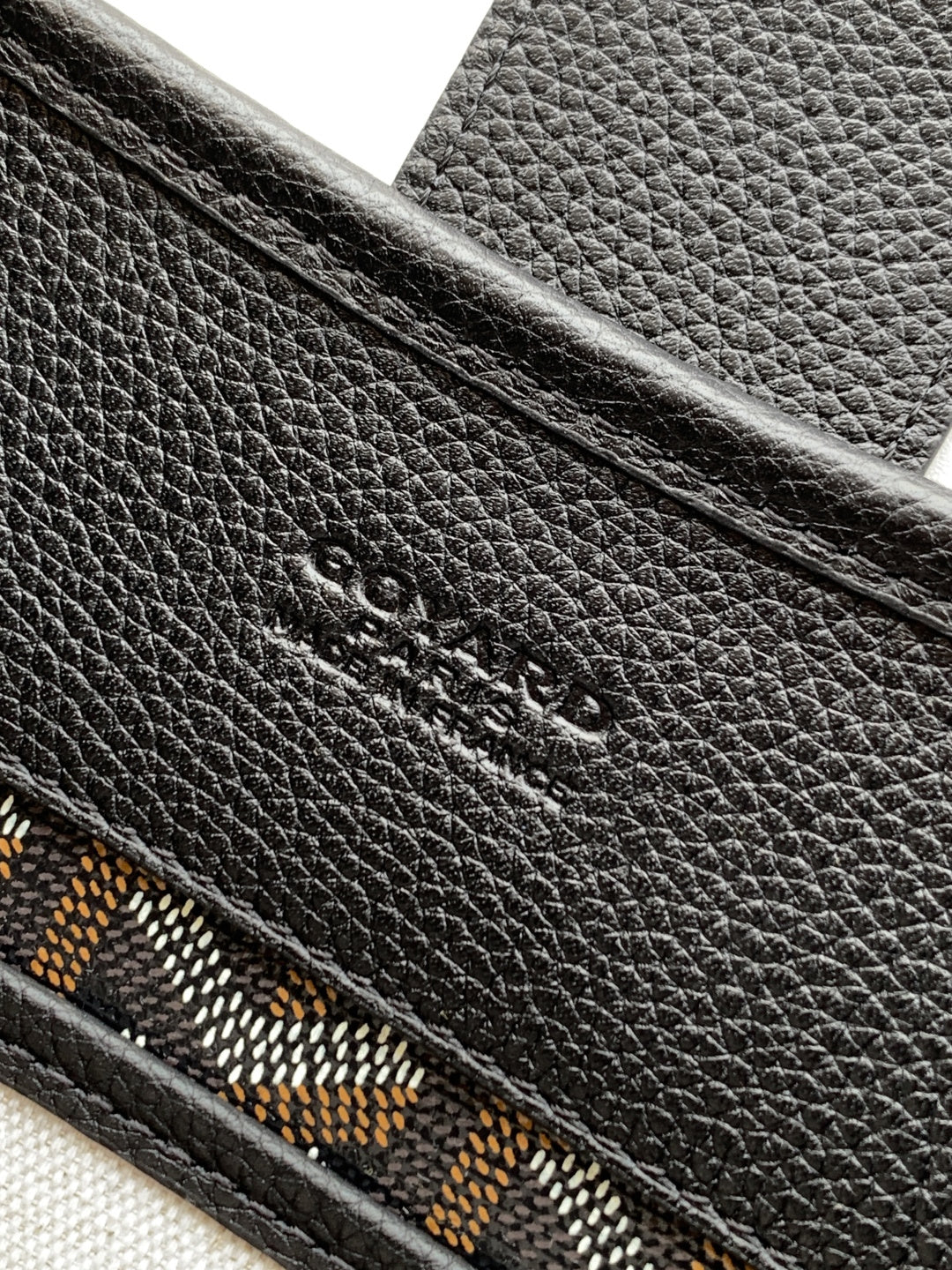 Black leather bag exterior with embossed logo detail and patterned trim