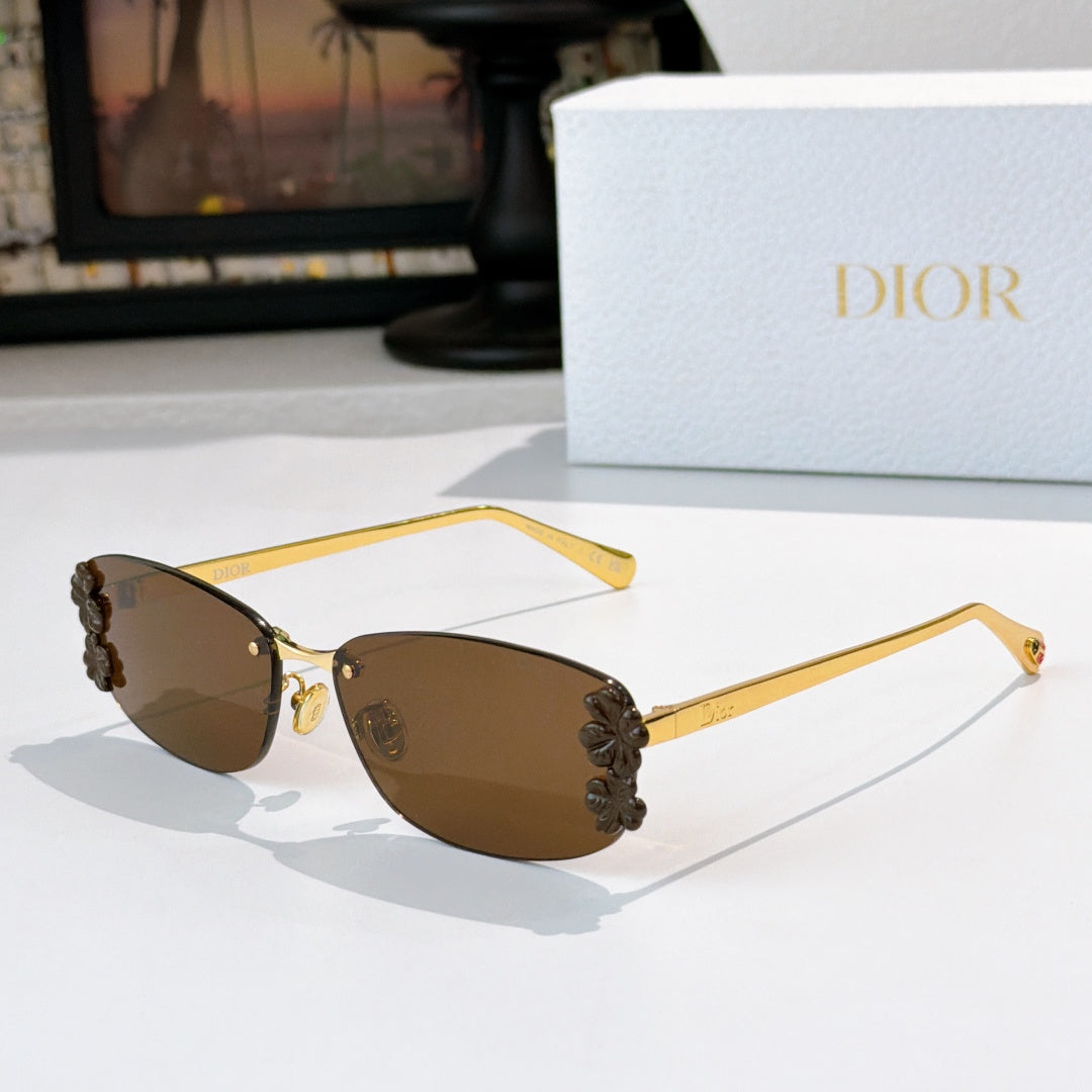 Dior sunglasses with gold frame, brown lenses, dark floral temple accents.