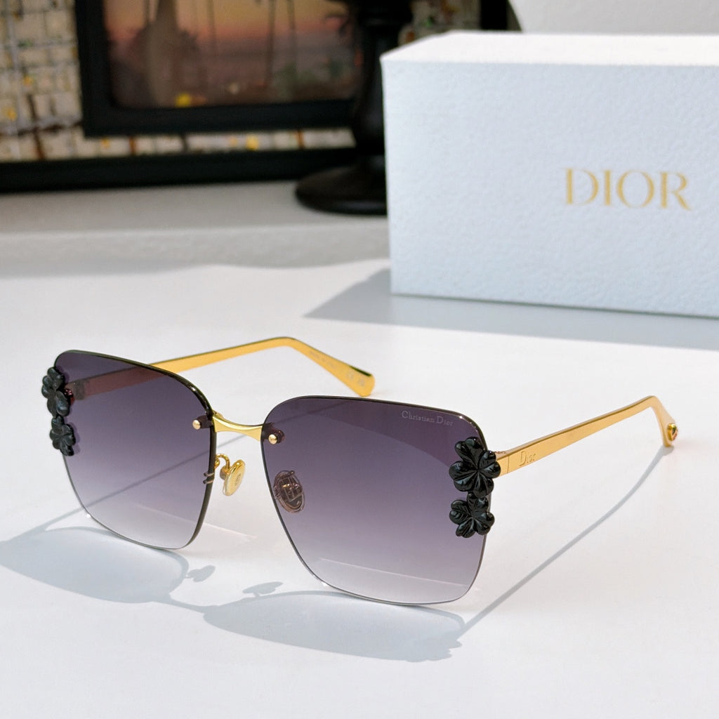 Dior sunglasses with gold frame and dark purple lenses, black floral temple accents.