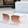 Dior sunglasses with gold frame and brown-pink gradient lenses, white floral temple accents.