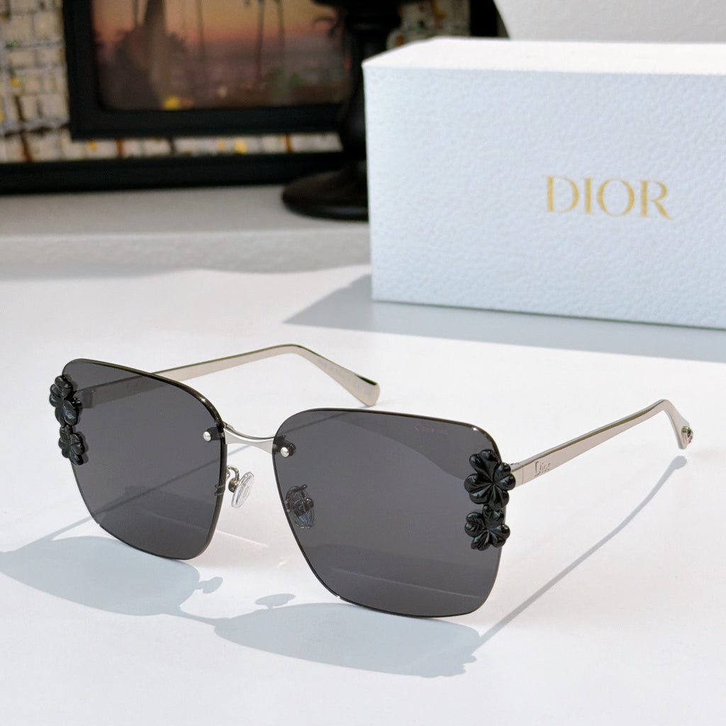 Dior sunglasses with gold frame and dark gray lenses, black floral temple accents.