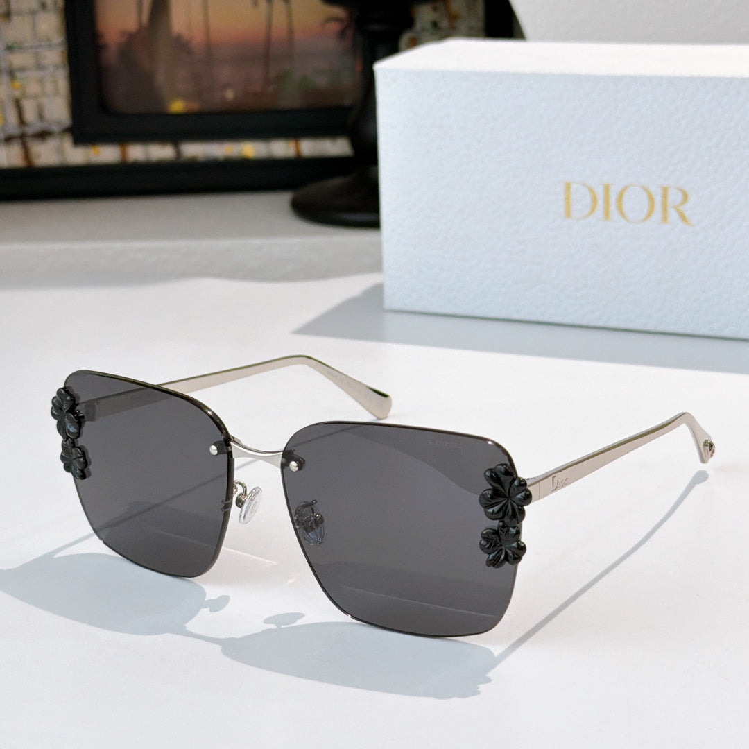 Dior sunglasses with gold frame and dark gray lenses, black floral temple accents.