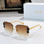 Dior sunglasses with gold frame and amber-brown lenses, black floral temple accents.