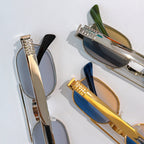 Sunglasses close-up: silver and gold frames with tinted lenses and temple details.