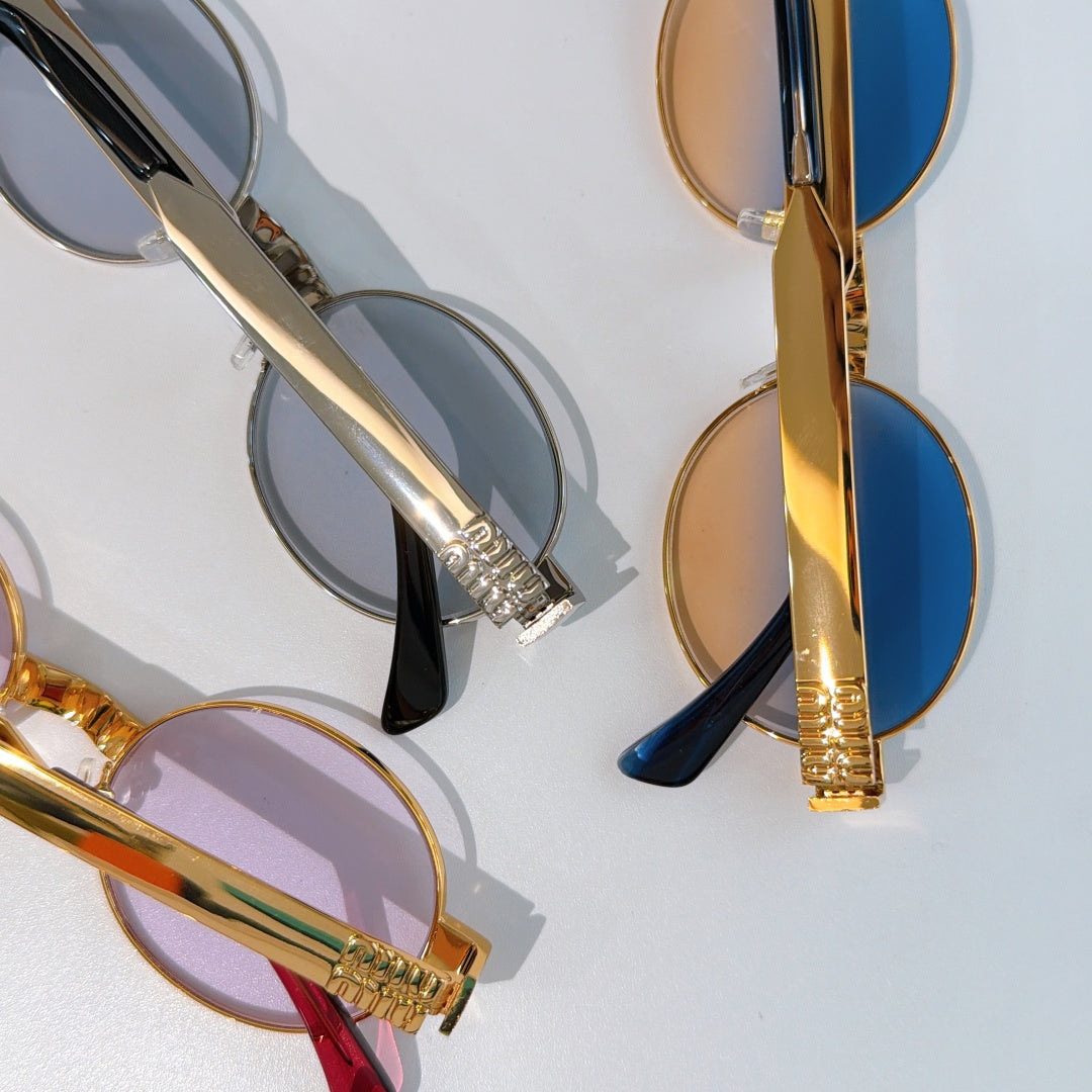 MiuMiu sunglasses close-up with gold arms and blue/gray tinted lenses