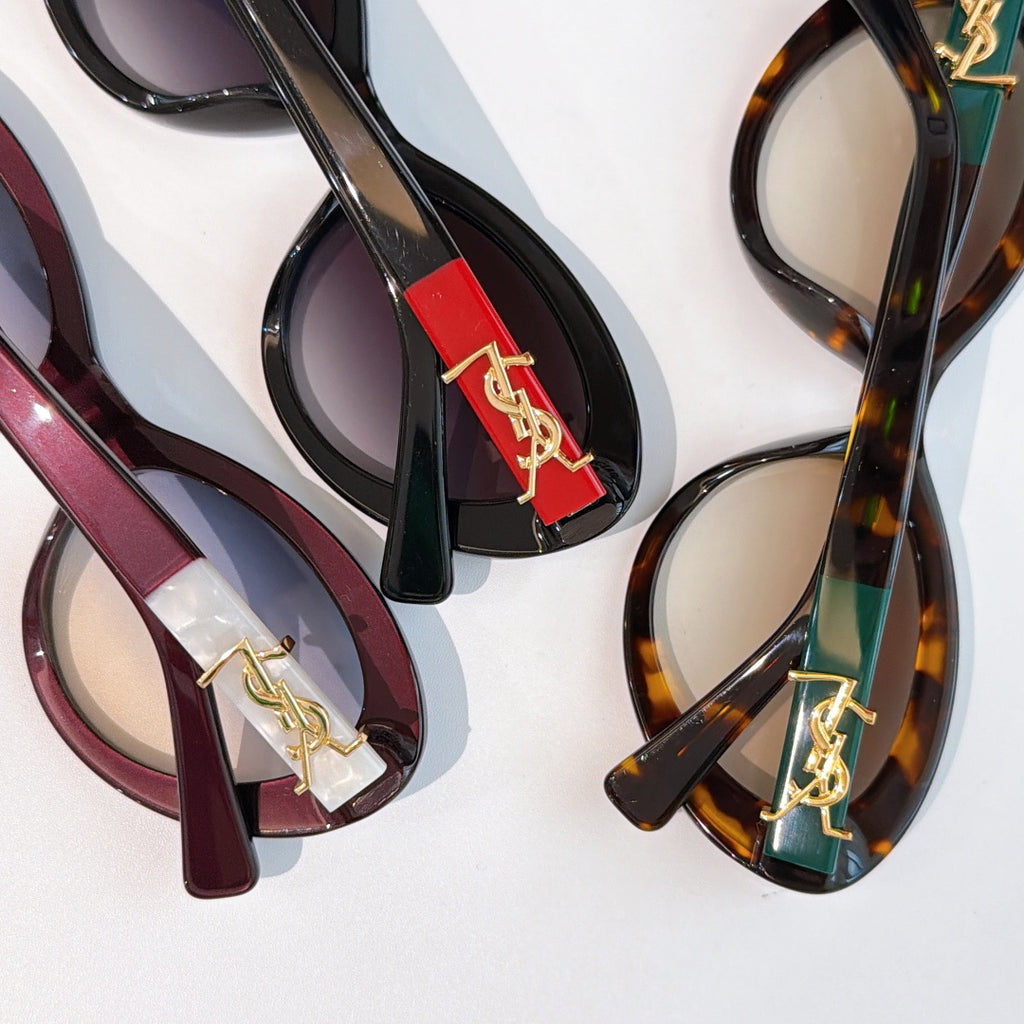 Assorted sunglasses close-up with colored frames and gold Saint Laurent logo bridges
