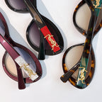 Assorted sunglasses close-up with colored frames and gold Saint Laurent logo bridges