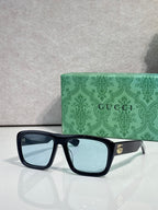 Gucci rectangular sunglasses with dark frames and light lenses; gold GG logo on temple