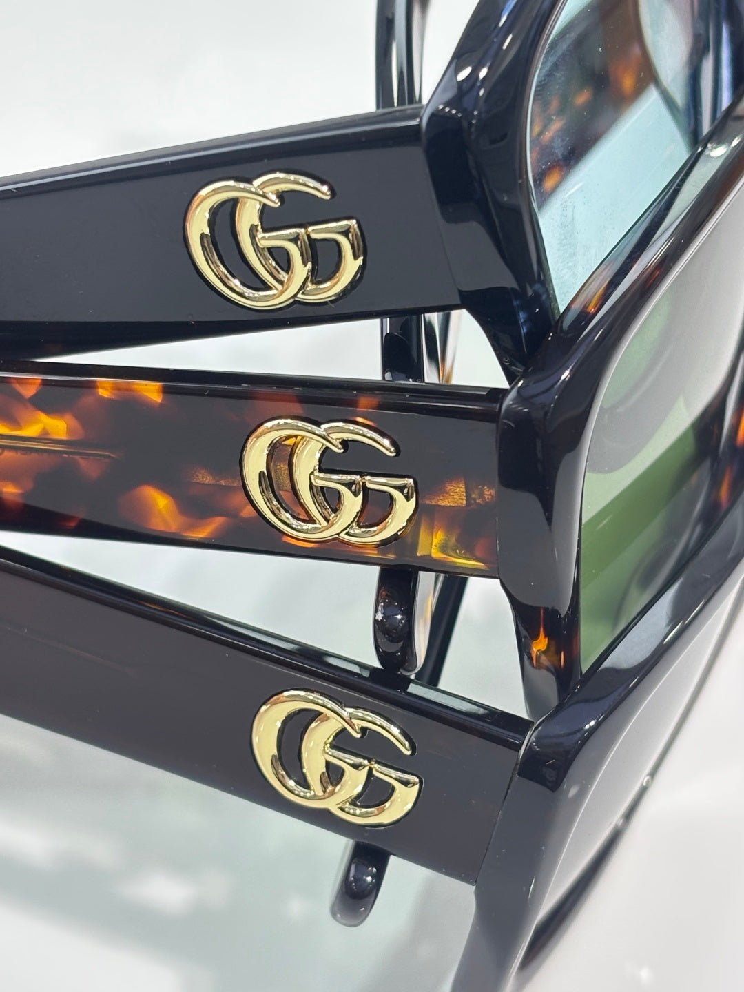 Gucci sunglasses temple close-up with gold GG hardware on dark frames