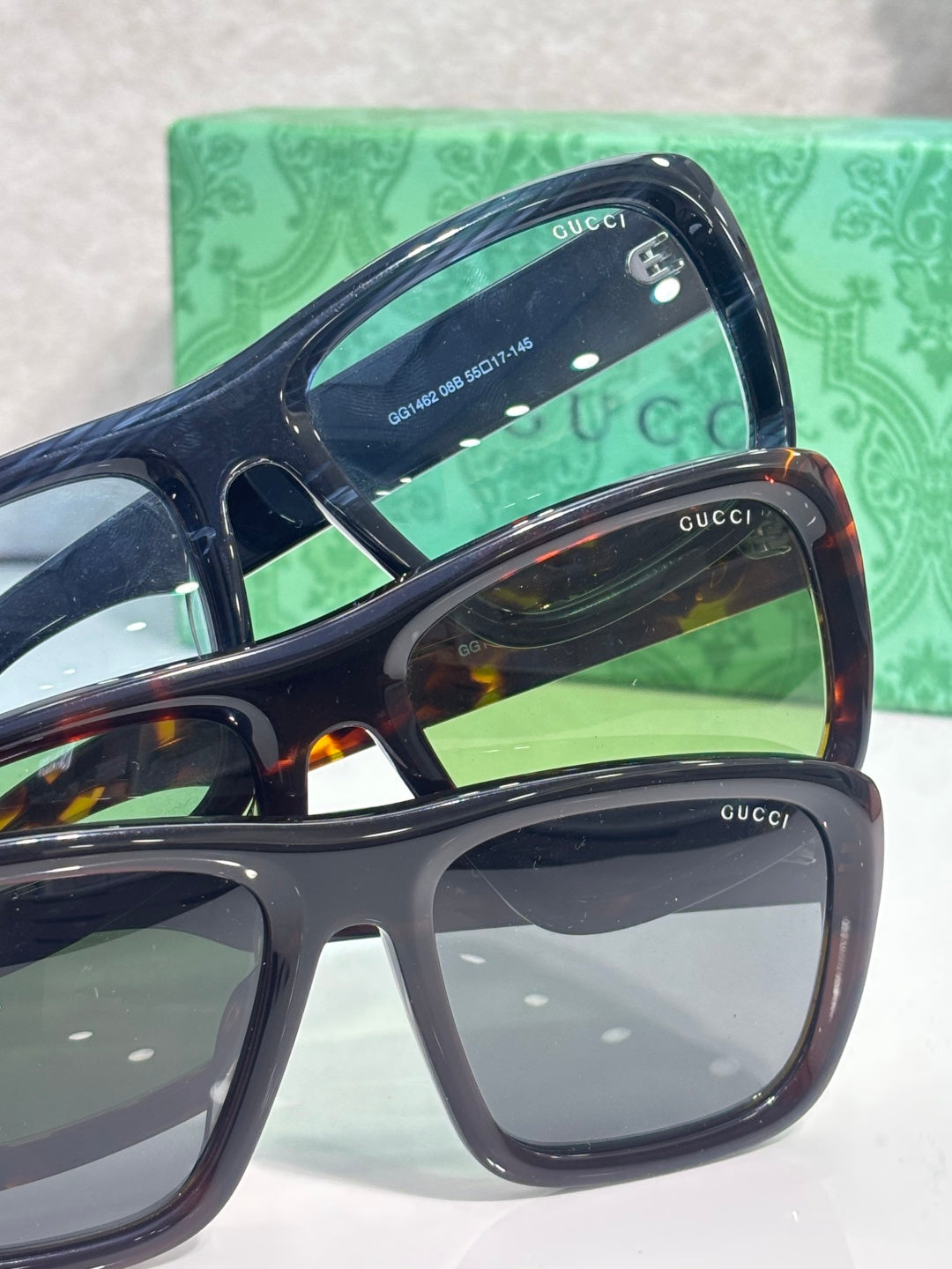 Gucci sunglasses side view with dark frames, stacked lenses, and green carrying case behind