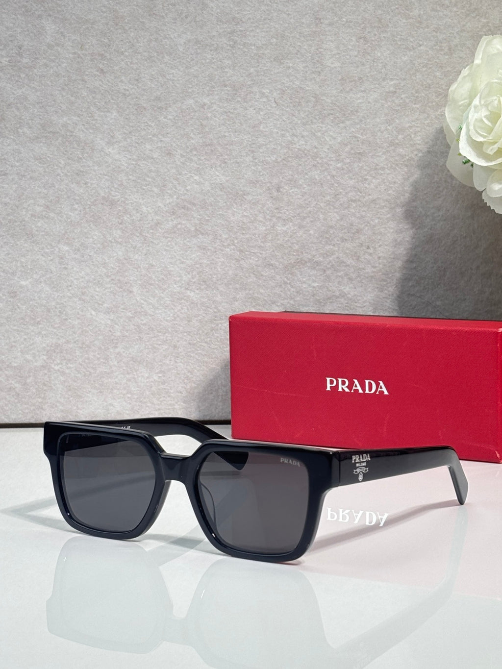 Prada black square sunglasses with dark lenses and temple branding