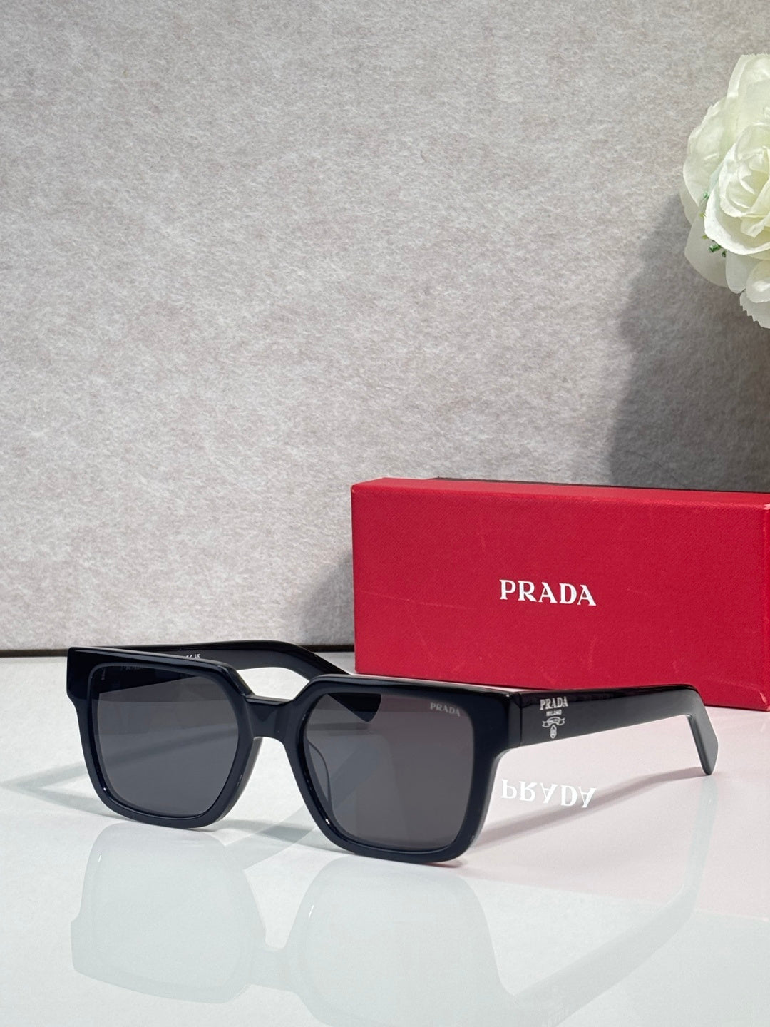 Prada black square sunglasses with dark lenses and temple branding