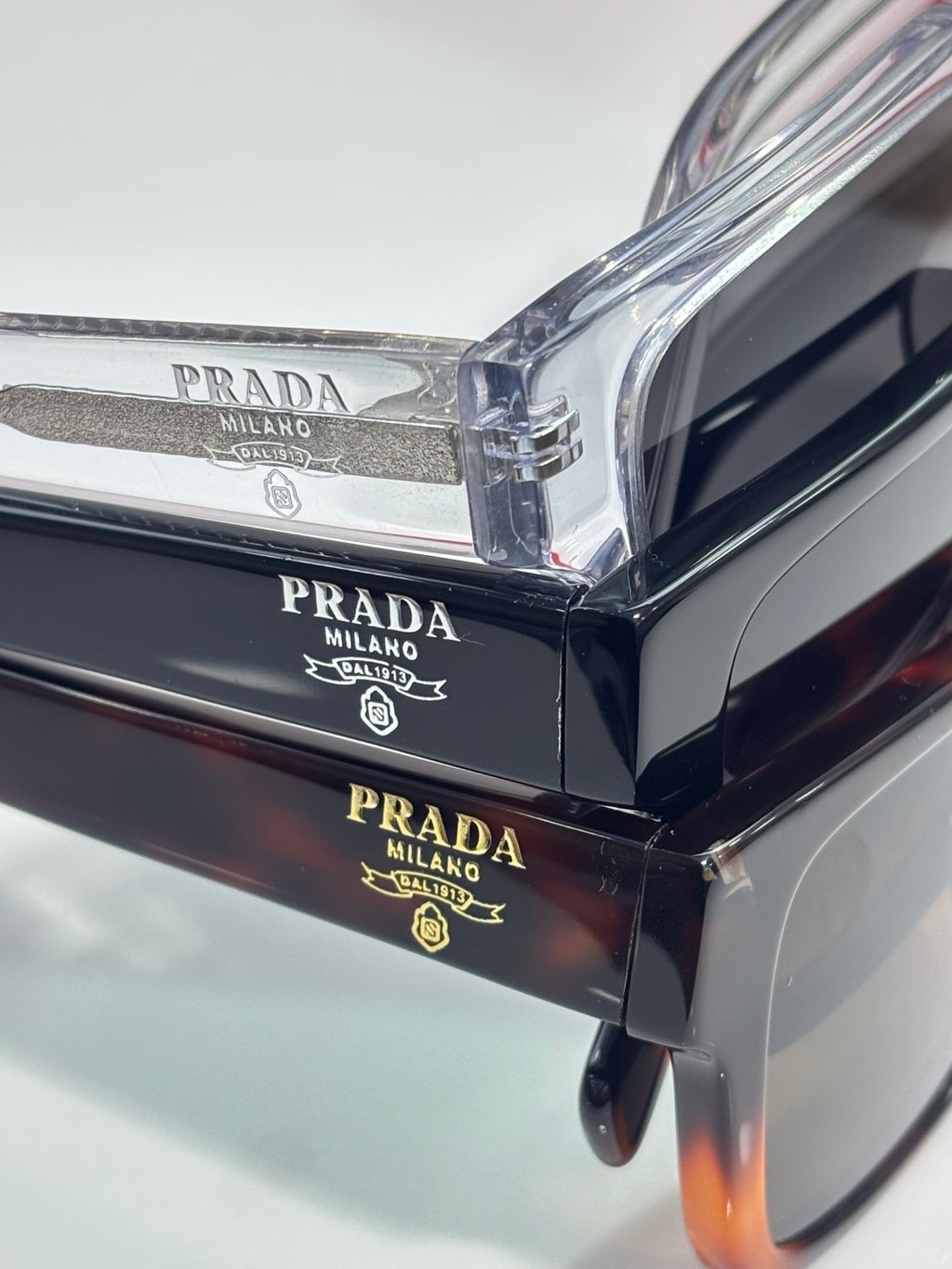 Prada navy sunglasses close-up showing engraved branding on the top bar