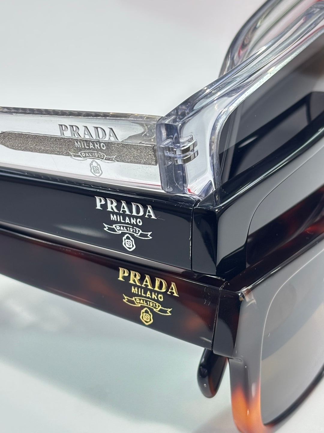 Prada navy sunglasses close-up showing engraved branding on the top bar