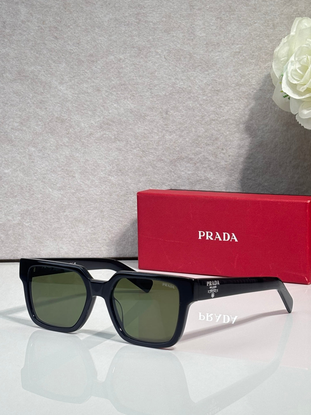 Prada black rectangular sunglasses with olive-tinted lenses and temple branding