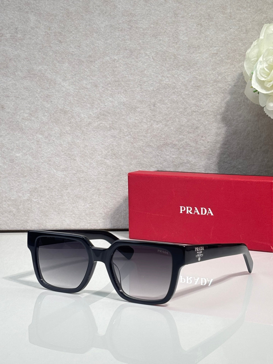 Prada black square sunglasses with dark lenses and logo on the temple