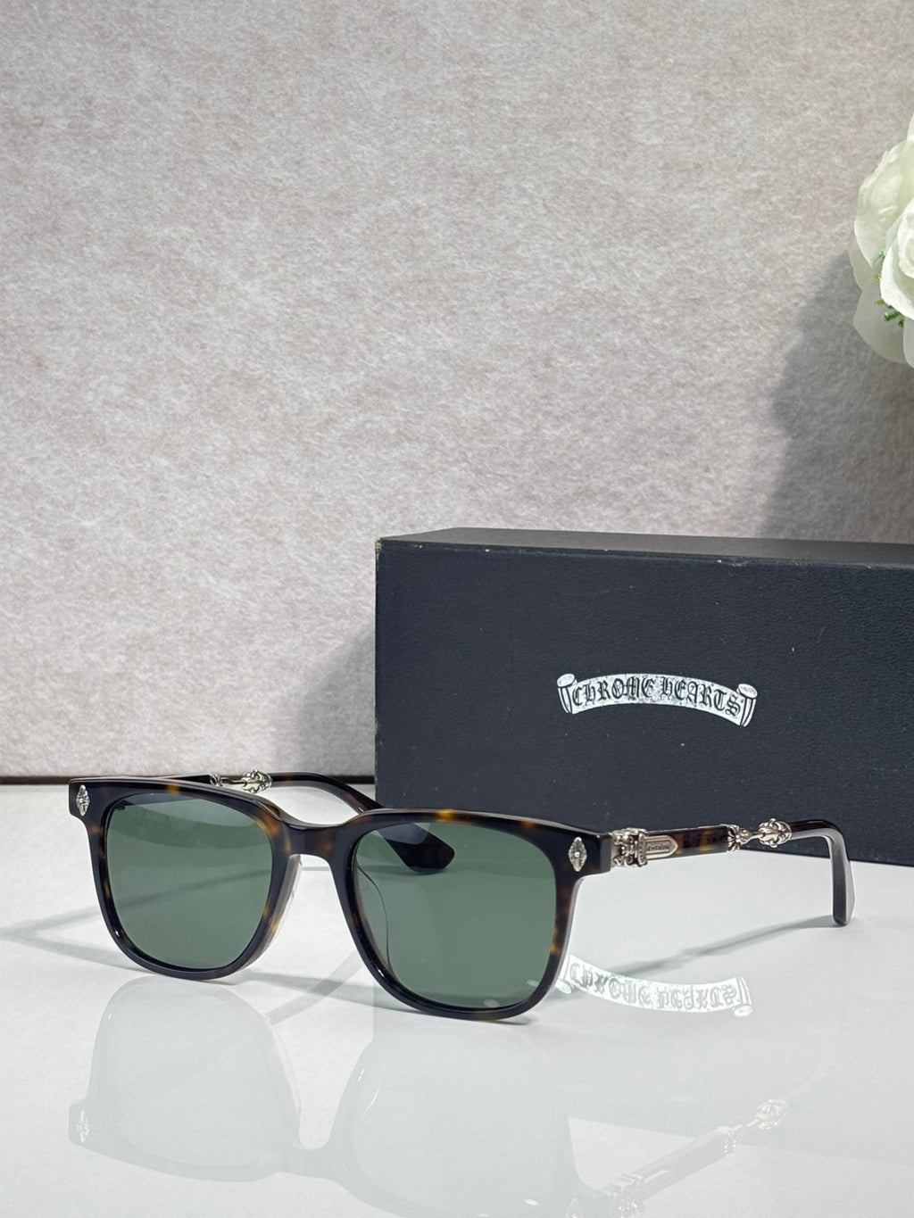 Sunglasses with dark frames and green lenses, gold-toned logo on temples.