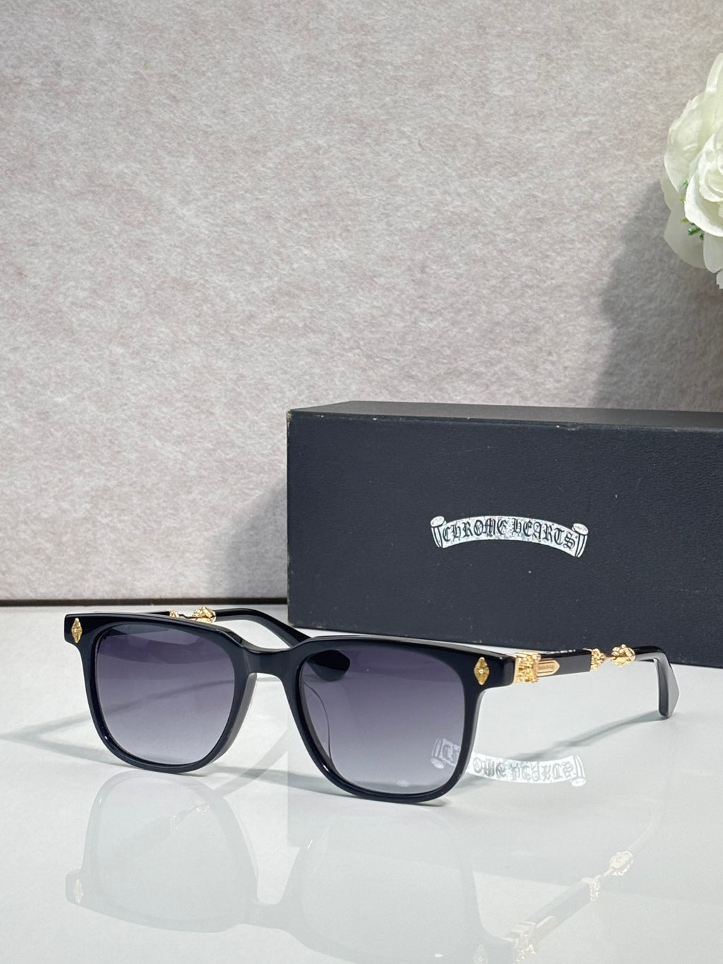 Sunglasses with dark frames and purple-tinted lenses, gold-toned temple accents.