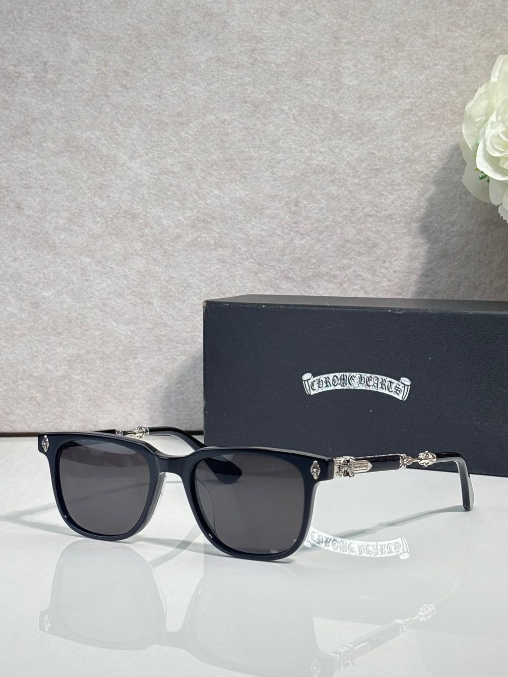 Sunglasses with black frames and dark lenses, metal logo accents on temples.
