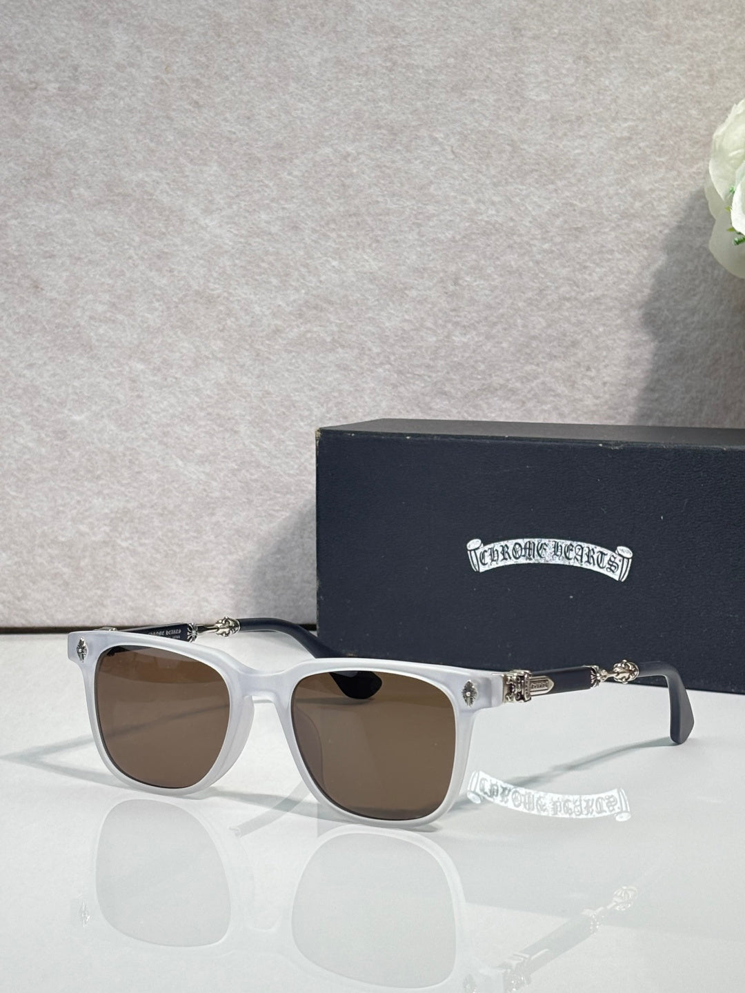 Sunglasses with light blue frames and brown lenses, gold-toned logo detail.