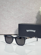 Sunglasses with dark frames and black lenses, gold-toned logo on temple.