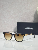 Sunglasses with dark frames and amber lenses, gold-toned detailing on temples.