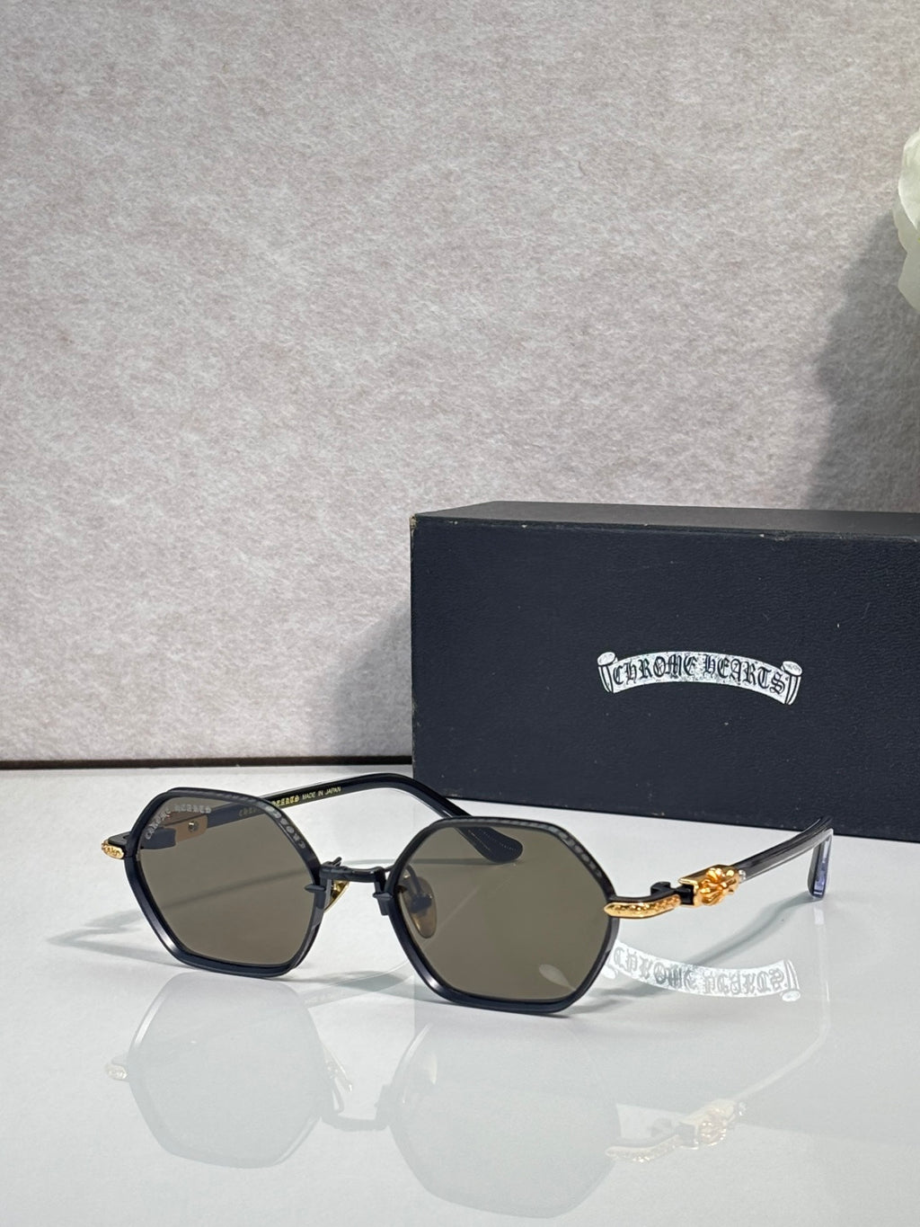Round sunglasses with black frames, dark lenses, and gold-toned temple details