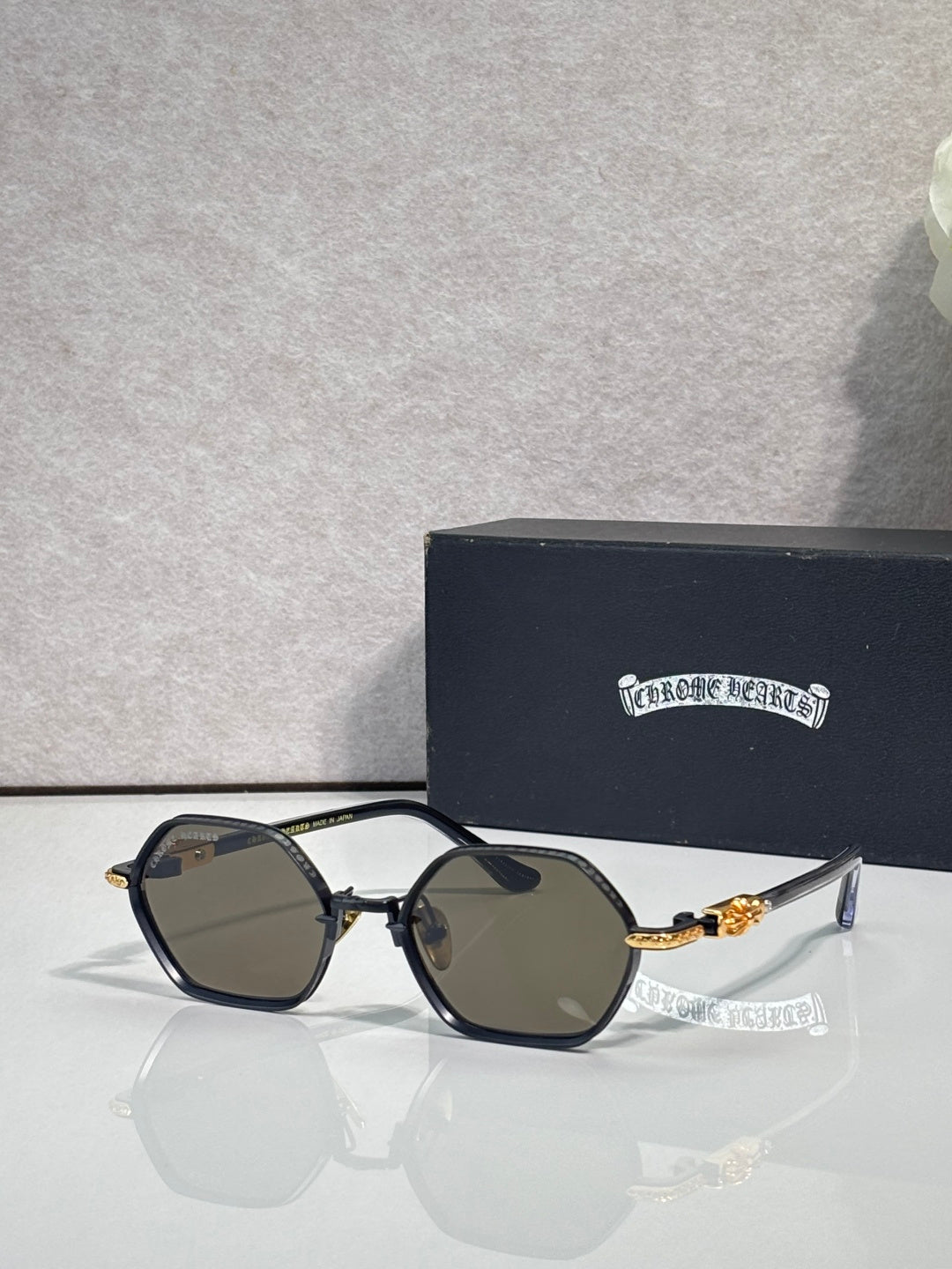 Round sunglasses with black frames, dark lenses, and gold-toned temple details