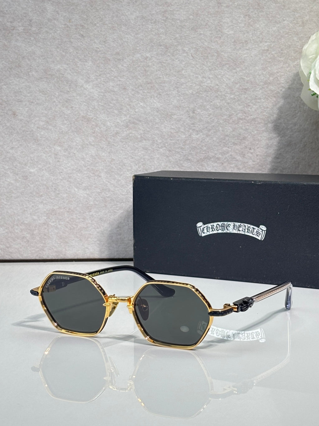 Round sunglasses with gold frames and dark lenses, clear bridge and ornate temples