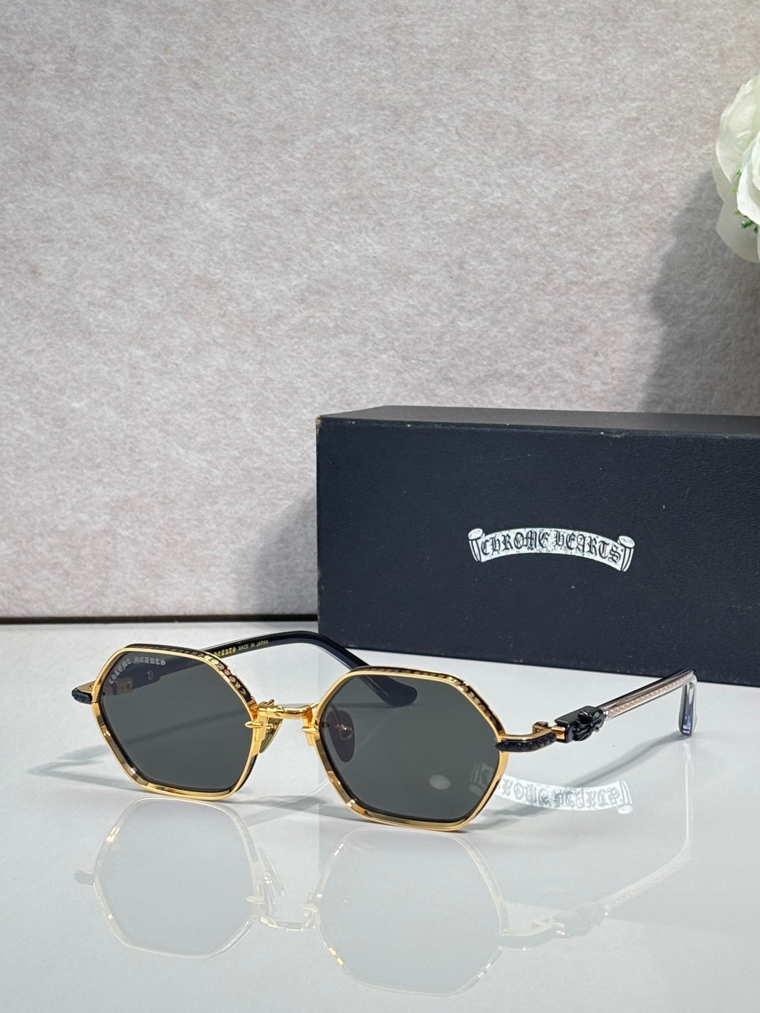 Round sunglasses with gold frames and dark lenses, clear bridge and ornate temples