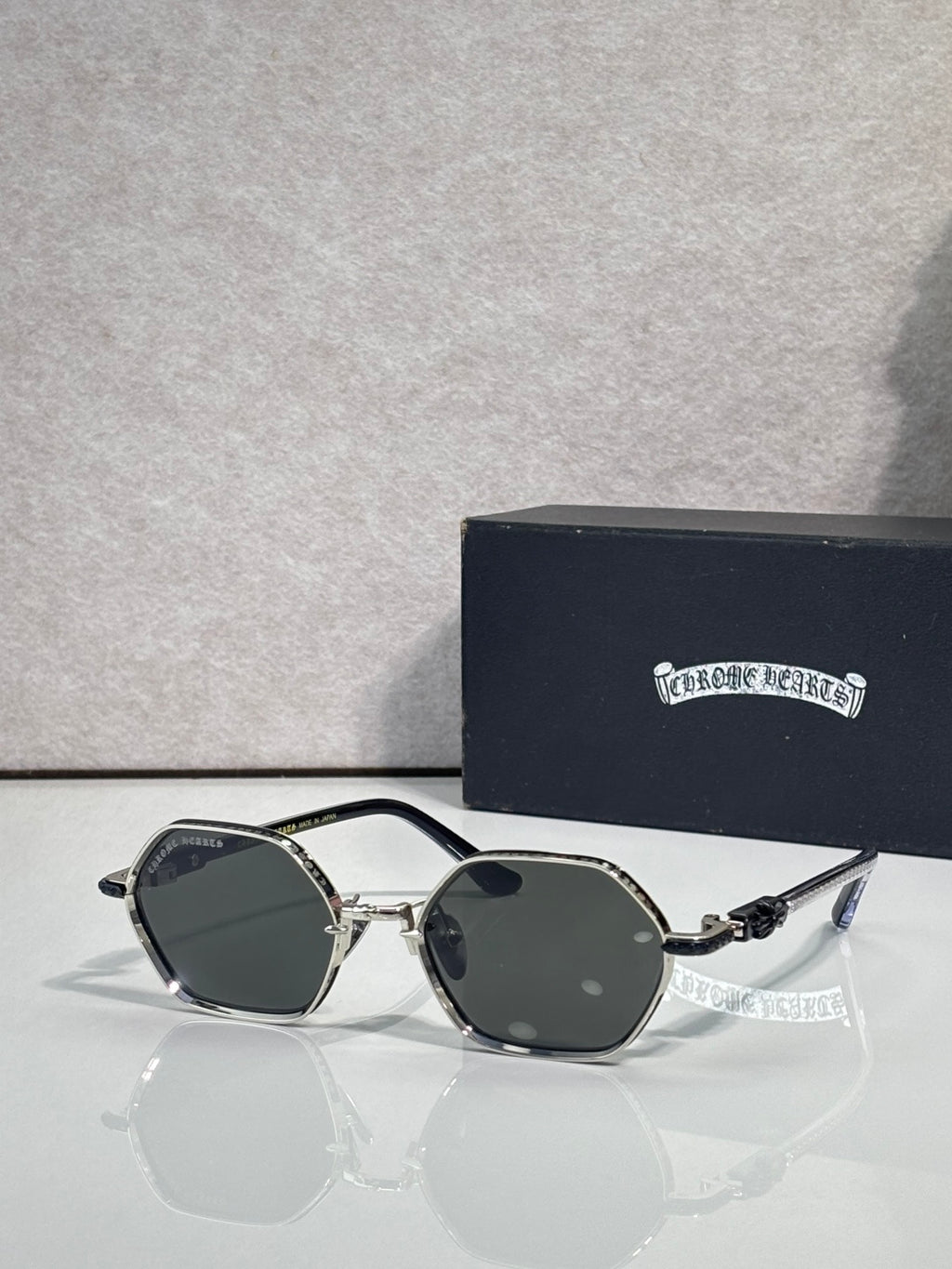Round sunglasses with black frames, dark lenses, and ornate temple accents