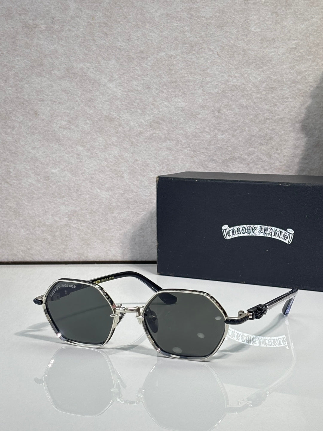 Round sunglasses with black frames, dark lenses, and ornate temple accents