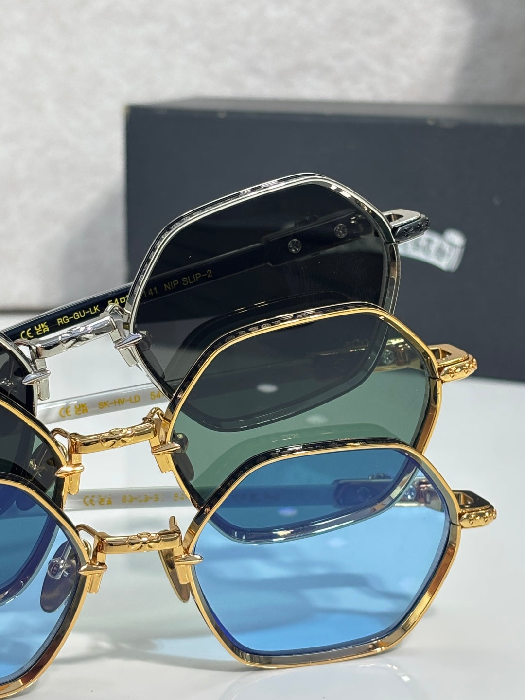 Pair of round sunglasses stacked with gold frames and blue/green tinted lenses